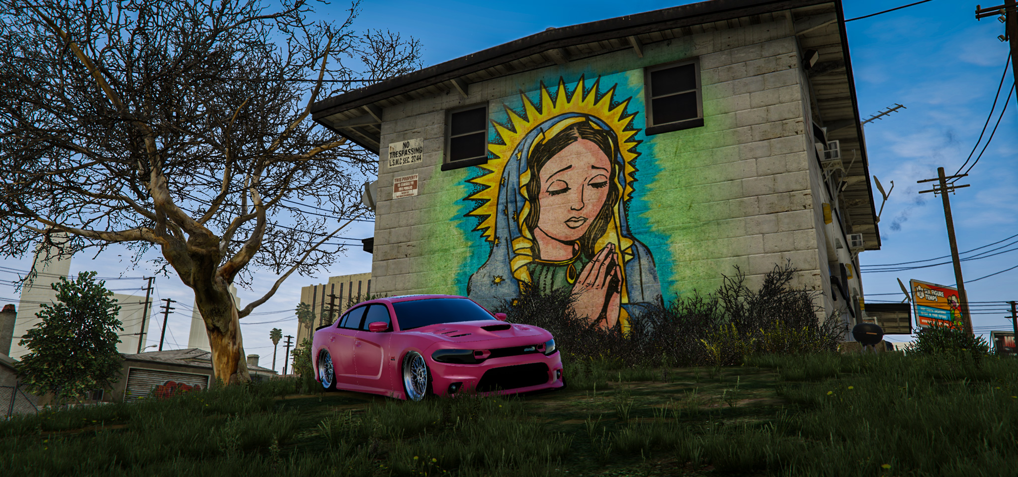 Pink stanced Dodge Charger parked on the grass before a Virgen de Guadalupe wall mural